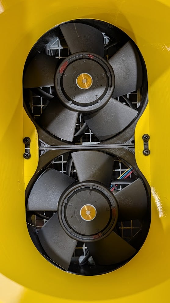 Close-up of the two 140 mm Antminer fans inside the yellow CryptoCloaks exhaust shroud